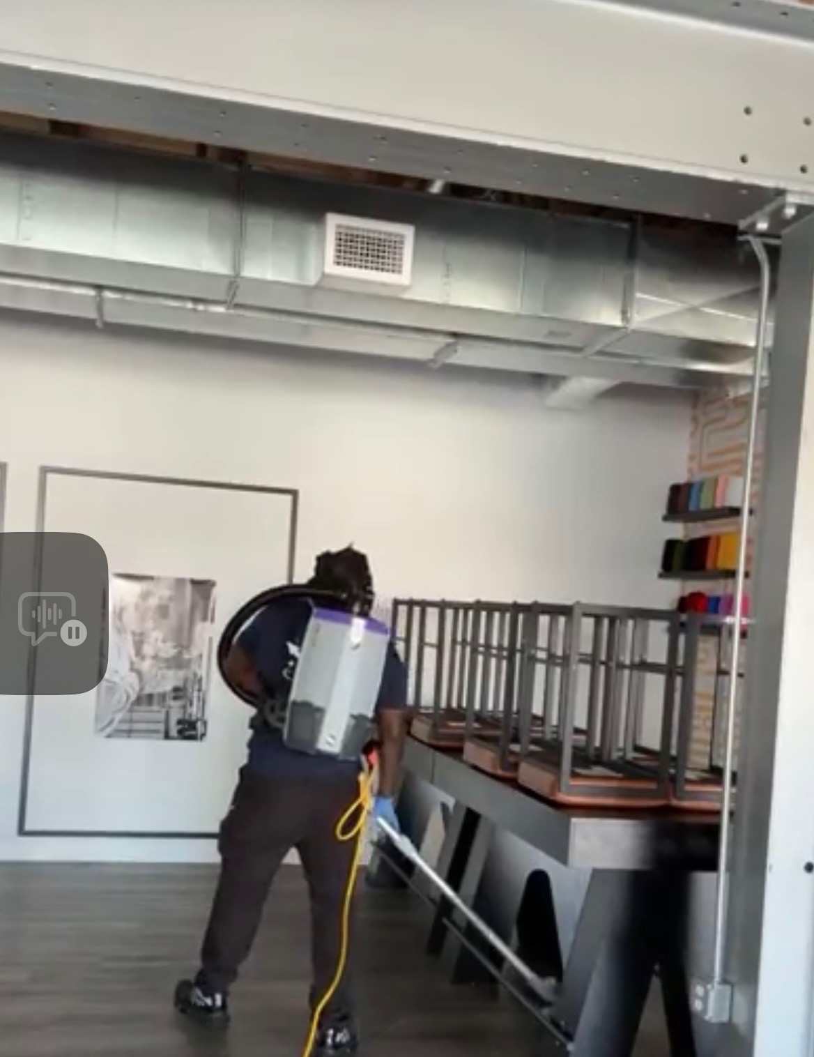 Next Level Commercial Cleaning professional using backpack vacuum under tables in a modern DC office
